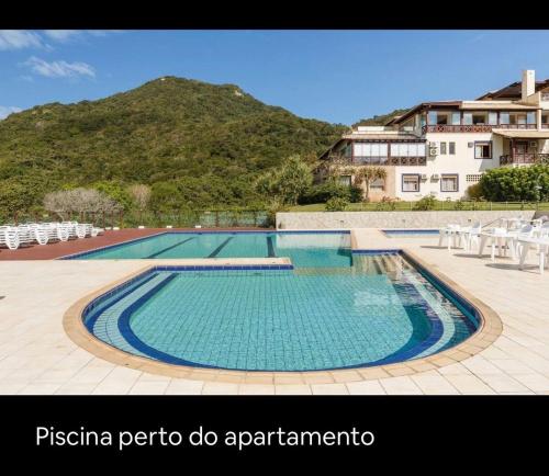 弗洛里亚诺波利斯UNICO Apto atendendo a 8 anos seguidos familias Dentro Resort Costao do Santinho COM RECEPÇÃO PERSONALIZADA COM MIMOS SURPRESA NO SEU CHECKIN xxxxxxxxxxxxxxx NOT ALL INCLUSIVE的一座大游泳池,后面是一座山