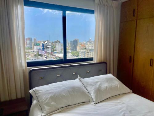 圣多明各Downtown Luxury Apt Naco: 2br 2ba的一张可从窗户欣赏到城市美景的床