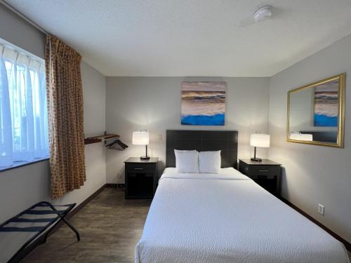 橘园橙园戴斯酒店的一间卧室配有一张大床和两盏灯。