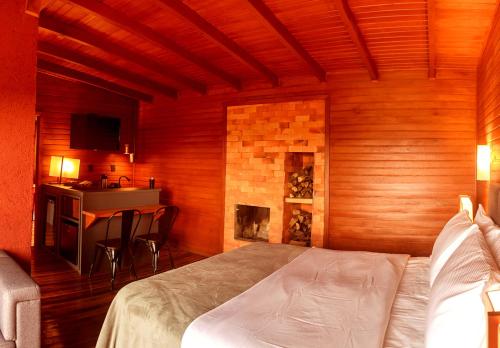 圣若阿金Vinícola D'alture - Cabana Casal -的带壁炉的客房内的一间卧室配有一张床