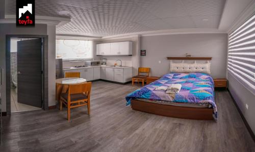 AtuntaquiTEYFA Hospedaje - Edificio的一间卧室配有一张床铺和一张桌子,还设有一间厨房