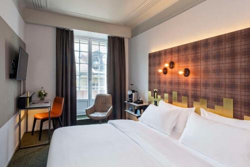 伯尔尼NH Bern The Bristol的酒店客房设有一张大床和一张书桌。