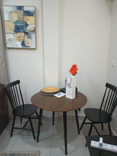 Himma's Apartments的一张桌子,两把椅子,花瓶上放着花