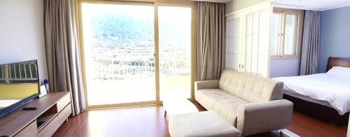 求礼郡K智异山家庭旅馆的带沙发和床的客厅以及窗户。