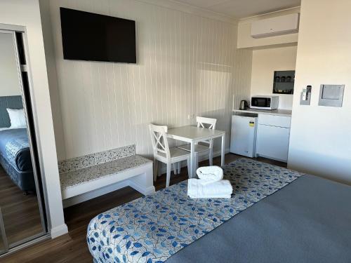 纽卡斯尔Surf Beach Motel Newcastle的一间小房间,设有厨房和一张桌子及一张床