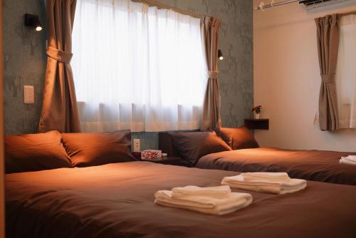 大阪nestay terrace house osaka tsutenkaku的一间卧室配有两张带毛巾的床