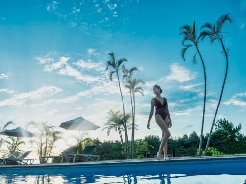 名户Oriental Hotel Okinawa Resort & Spa的站在游泳池边缘的比基尼的女人
