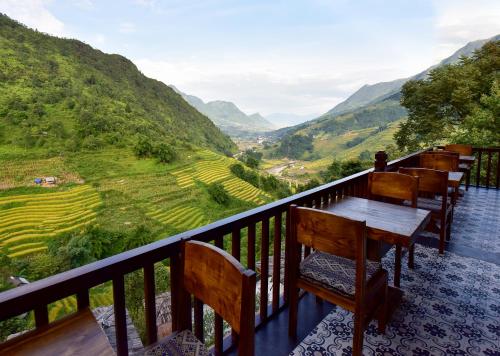 萨帕Maison de Lao Chai的阳台配有桌椅,俯瞰着山谷