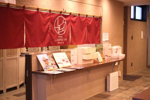 京都HOTEL LEGASTA KYOTO SHIRAKAWA SANJO的室内有红旗的柜台