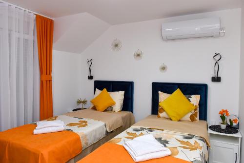 KuršumlijaApartmani Simić的橙色和白色的客房内的两张床