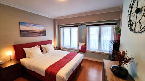 奥斯坦德加的夫酒店的一间卧室设有一张大床和两个窗户。