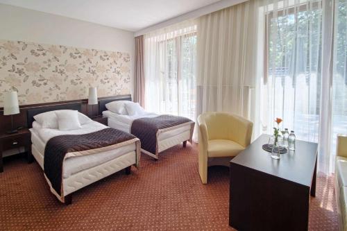 图拉瓦Hotel Zacisze的酒店客房设有两张床和一张桌子。