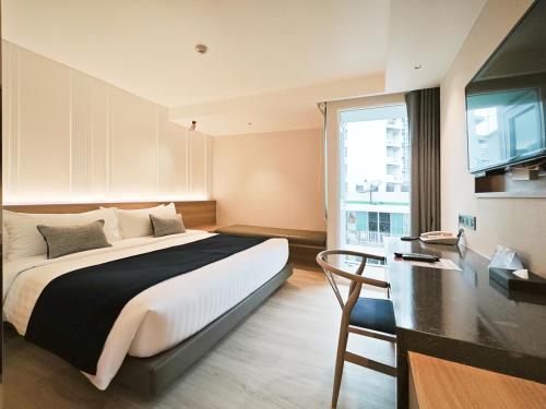 曼谷康帕斯酒店集团素坤逸13巷娜娜柑橘酒店的一间卧室配有一张床、一张书桌和一台电视