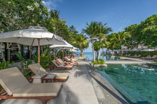 高兰Layana Resort & Spa - Adult Only - SHA Extra Plus的度假村的游泳池,那里有人坐在椅子上,还有一把遮阳伞