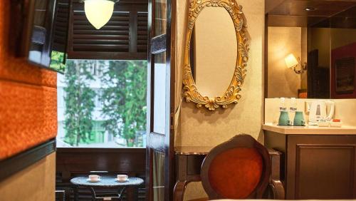 新加坡Nostalgia Hotel的浴室设有镜子和靠窗的椅子