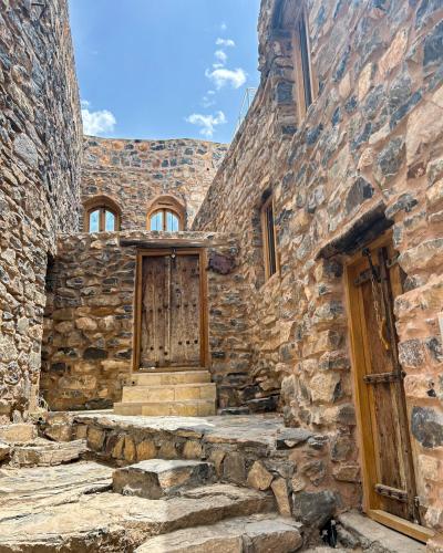 Al ‘AqarHanging Terraces المدرجات المعلقة的一座古老的石头建筑,设有木门和楼梯
