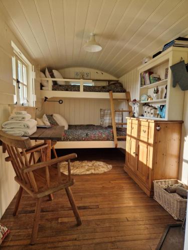 科姆堡The Delkin Shepherds Huts Castle Combe的一间客房配有书桌和一张位于客房内的床。