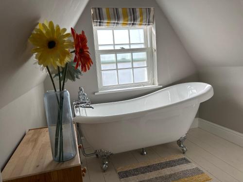 灵顿Stunning period cottage的带窗户的浴室内的白色浴缸