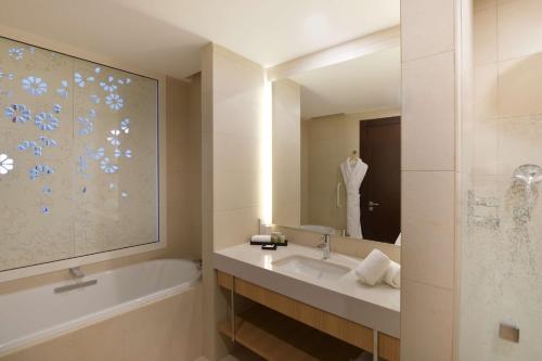 塔哈佐特Hilton Taghazout Bay Beach Resort & Spa的带浴缸、水槽和镜子的浴室