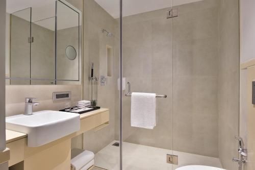 阿伯来Citadines Arpora Nagoa Goa的一间带水槽和玻璃淋浴的浴室