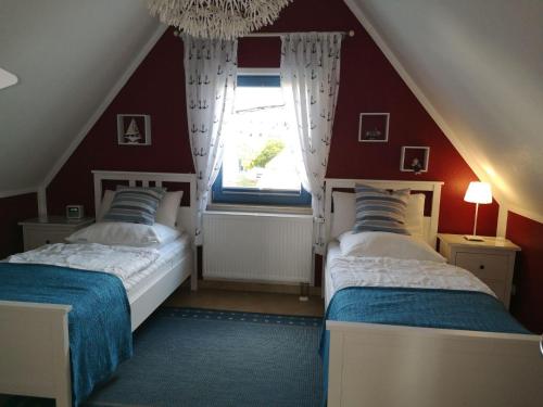 格洛韦Ferienhaus-Seehund的宿舍间的两张床,设有红色的墙壁和窗户。