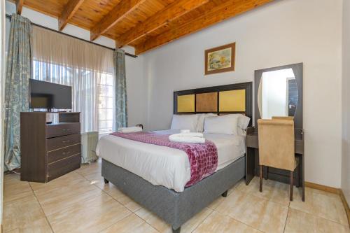 SandtonRoyal Olympia Lodges & Safaris RSA的一间卧室配有一张床、一张书桌和一台电视