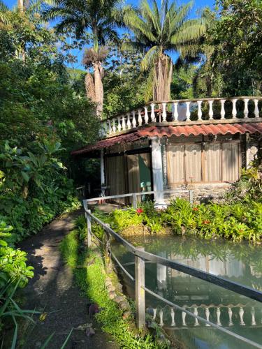 San GerardoBotanica Gardens and Eco Lodge的前面有池塘的小房子