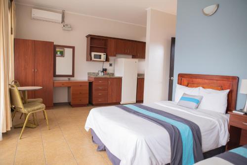 迦太基萨尔瓦多古阿可酒店餐厅的一间带一张床和一张书桌的卧室和一间厨房