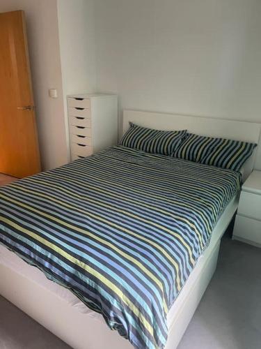 伦敦Luxurious NEW 2 Bed apartment的卧室内的一张带条纹棉被的床