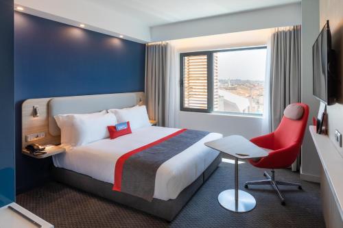 波尔图Holiday Inn Express Porto City Centre, an IHG Hotel的酒店客房,配有一张床和一张红色椅子