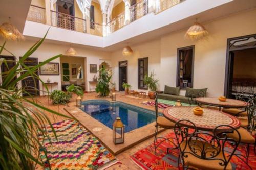 马拉喀什Riad en Exlusivité à 5min de la place jamaa el fna的客厅设有游泳池、桌子和椅子