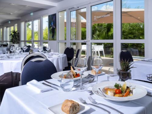 拉波勒拉波勒金郁金香酒店 的一间用餐室,配有带食物盘的白色桌子