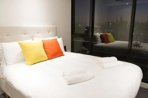 墨尔本Modern Spacious 2BD2Bath - Stunning City Views!的一张白色的床,上面有两个色彩缤纷的枕头