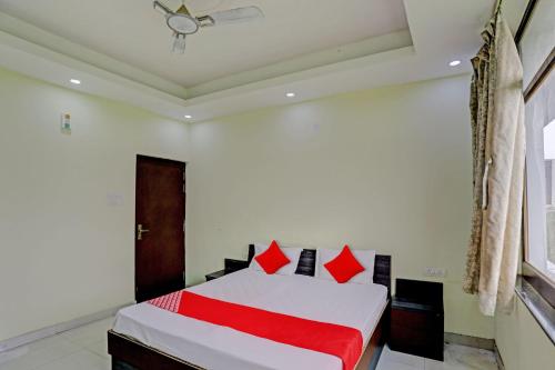 坎普尔OYO Flagship Shree Shyam Kripa Hotel And Restaurant的卧室配有带红色枕头的白色床