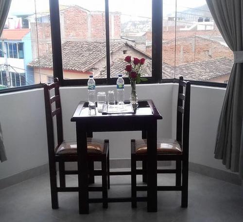奥塔瓦洛Coraza Hotel的一张桌子,两把椅子,花瓶上放着鲜花