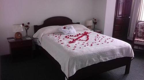 奥塔瓦洛Coraza Hotel的一张床上有红色玫瑰花瓣的床
