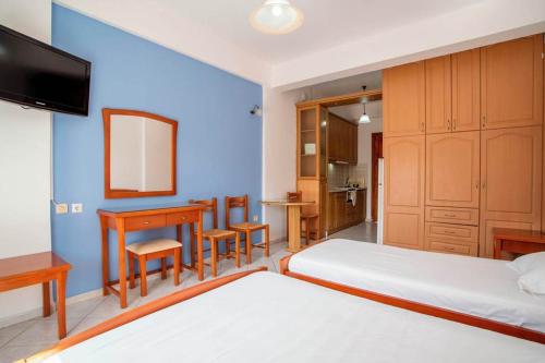 菲尼孔塔卡里斯提旅馆的一间卧室配有两张床、一张桌子和一张书桌