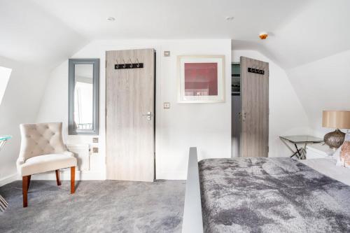 布兰德福德福鲁姆The Secret, Stylish & Spacious En Suite in Blandford Forum, Dorset的一间卧室设有两扇门、一把椅子和一张床