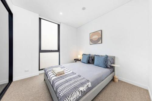 悉尼Adorable 2B Apt near Macquarie Uni的白色卧室配有一张带蓝色枕头的大床