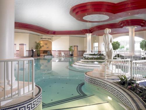 科克Rochestown Park Hotel & Leisure Centre的一座位于酒店中间的游泳池,设有雕像