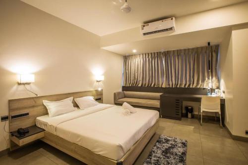 马尔冈Coastal Pearl Hotel Margao Railway Station的一间卧室配有一张床、一张书桌和一个窗户。