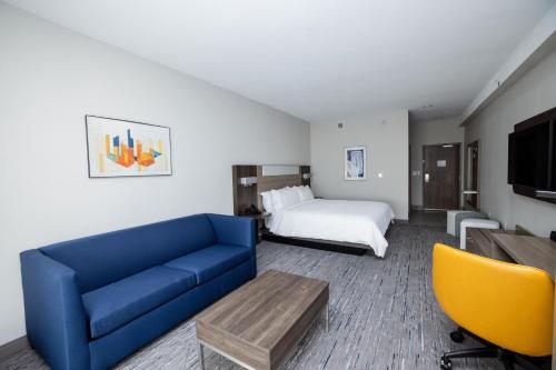 坦帕Holiday Inn Express & Suites Tampa Stadium - Airport Area, an IHG Hotel的酒店客房配有蓝色的沙发和床。