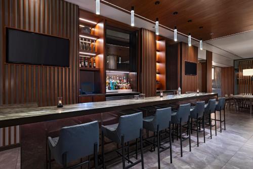 休斯顿AC Hotel by Marriott Houston Downtown的餐厅内的酒吧配有椅子和电视