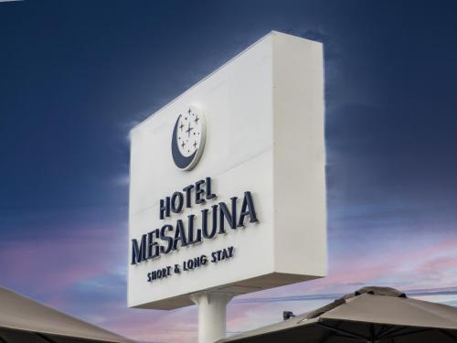 华雷斯城Hotel Mesaluna Short & Long Stay的挂着时钟的酒店标志