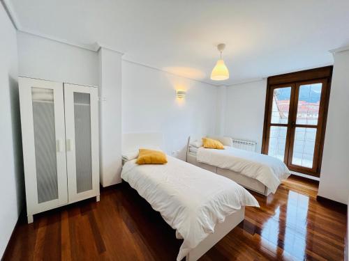 拉马莱斯德拉维克托里亚Excelente apartamento con garaje y piscina的配有白色墙壁和木地板的客房内的两张床