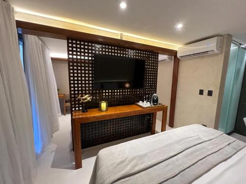 费尔南多 - 迪诺罗尼亚Pousada Naonda的一间卧室配有一张床,墙上配有电视