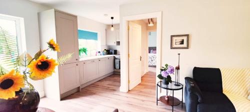 戈尔韦Butterfly Guesthouse - Entire Home within 5km of Galway City的厨房以及带向日葵花瓶的起居室。