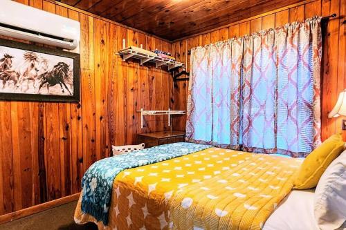 温泉城#08 - One Bedroom Lakeview Cottage-Pet Friendly的卧室配有一张床铺,位于带木墙的房间内