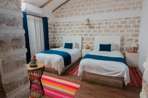Colchani萨尔露娜萨拉达酒店的一间卧室设有两张床和砖墙