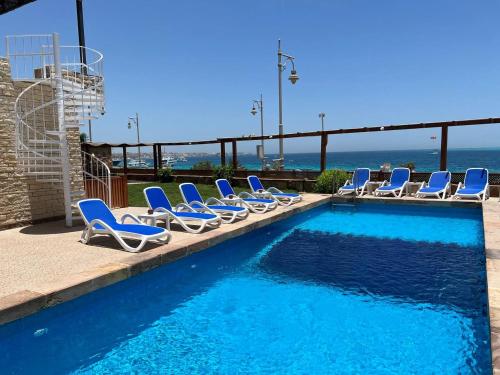 赫尔格达Serafy City Center Hostel and Pool for Foreigners Adults Only的一个带椅子的游泳池,背景是大海